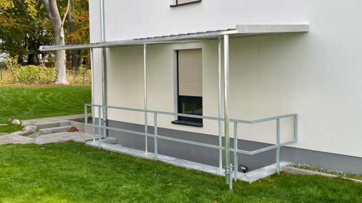 Aluminium Unterstand bedeckt mit Trapezblechen in Silber vor einem Kellereingang